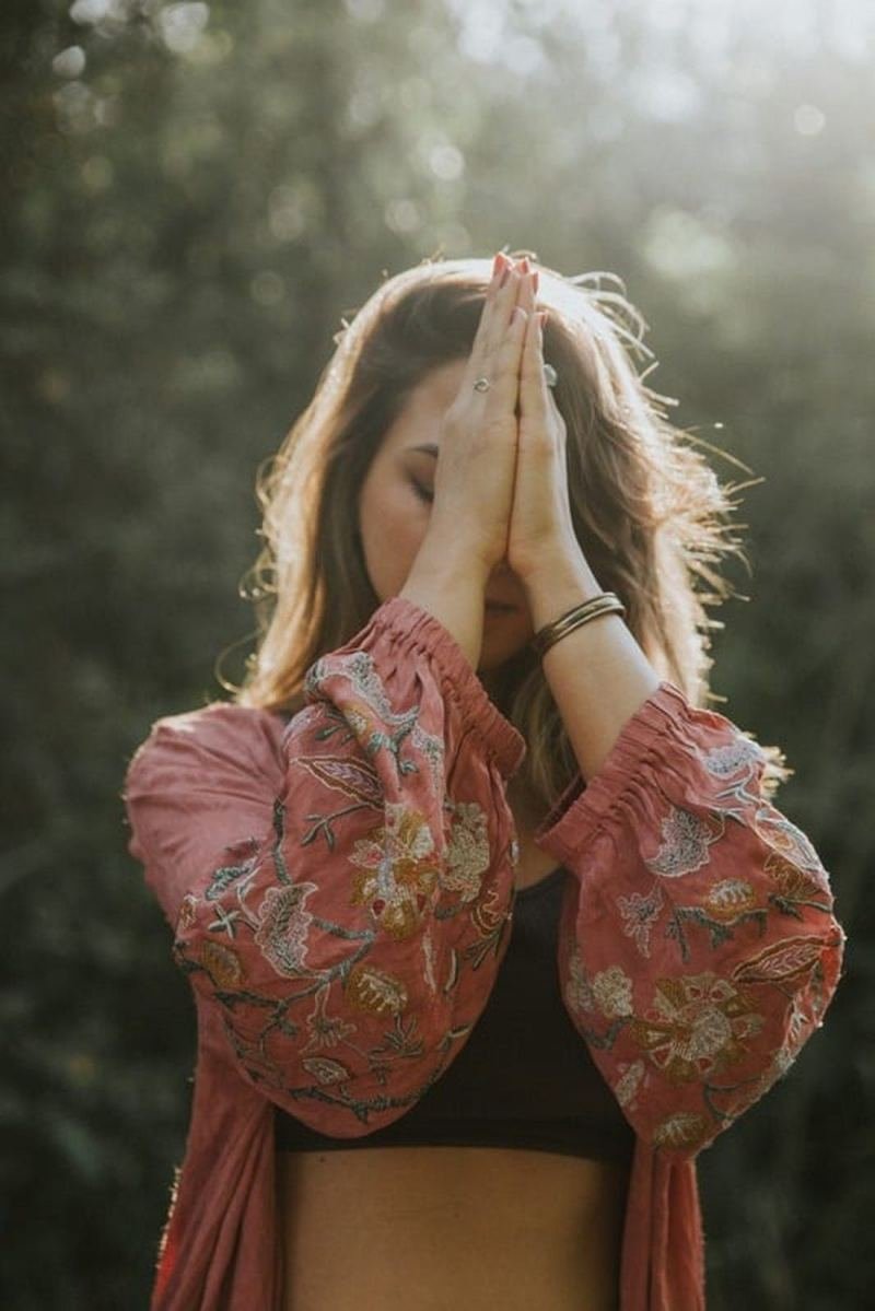 Hands in prayer wearing a flower crown